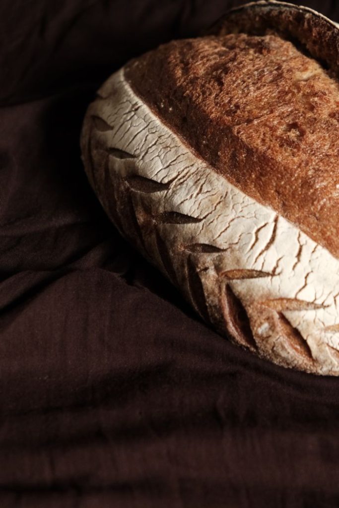 A close-up of artisanal bread with a crusty texture on a dark rustic background.