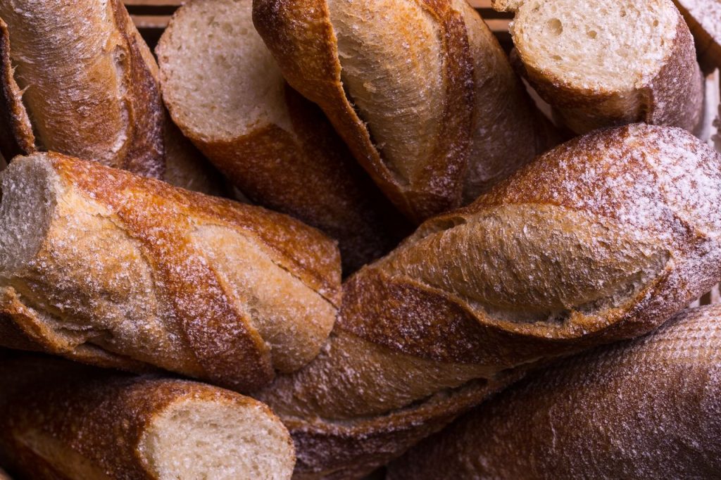 Rustic fresh baguettes in a basket, showcasing crusty textures and artisanal baking.