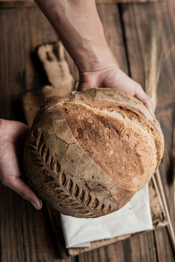 hands-holding-freshly-baked-artisan-sourdough-bread-pdthpng7jbe