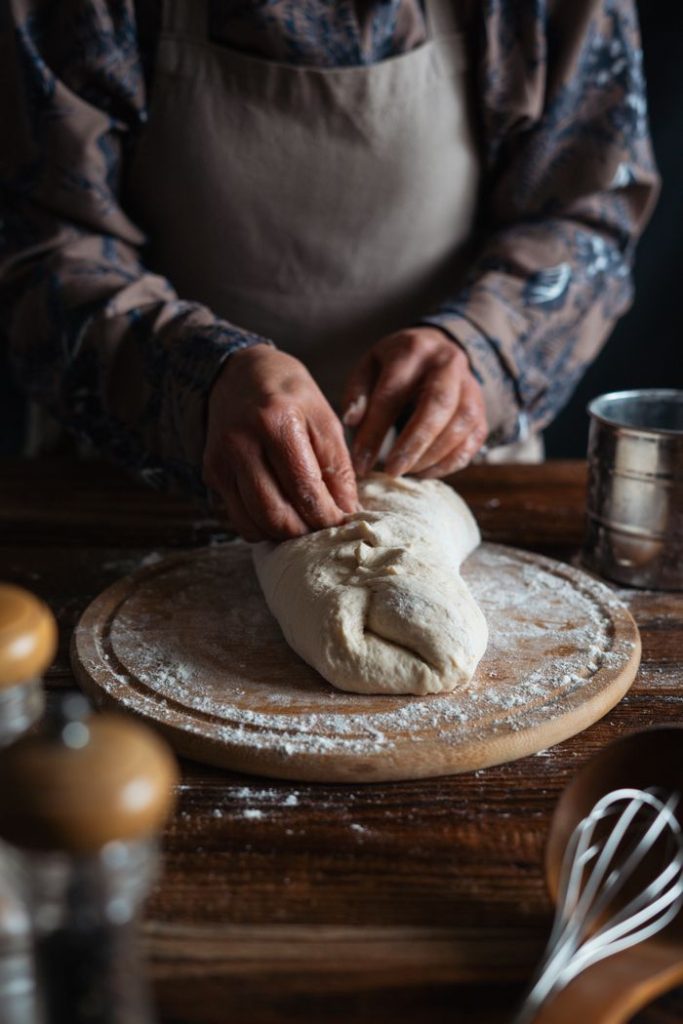 Baker kneading dough in a cozy kitchen setting, showcasing artisanal bread-making.