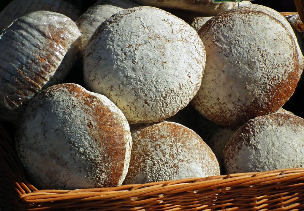 Round artisan bread loaves in a wicker basket, showcasing rustic textures and crusty surfaces.