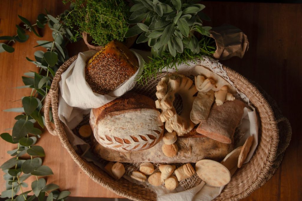 A wicker basket filled with various breads and fresh herbs, creating a rustic look.